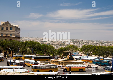 Der Busbahnhof in Valletta ist ein Kreisverkehr an der Triton-Brunnen.  Die klassischen Busse in orange und gelb Surround-Brunnen. Stockfoto