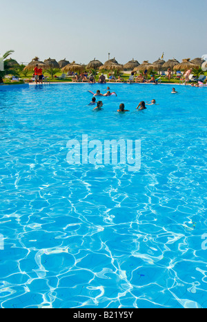 Vertikale Weitwinkel ein belebtes Hotel Swimming Pool umgeben von vielen Rasen Sonnenschirme und Sonnenliegen Stockfoto