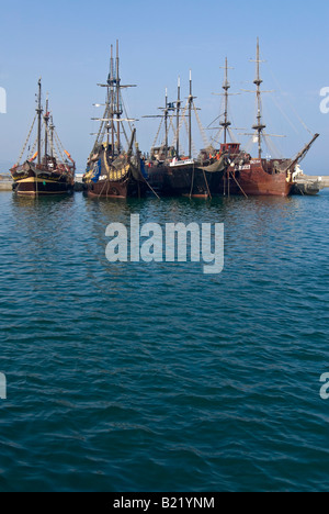 Vertikale Ansicht von vier Galeone Stil Piratenschiffen vertäut nebeneinander in einem Hafen vor blauem Himmel. Stockfoto