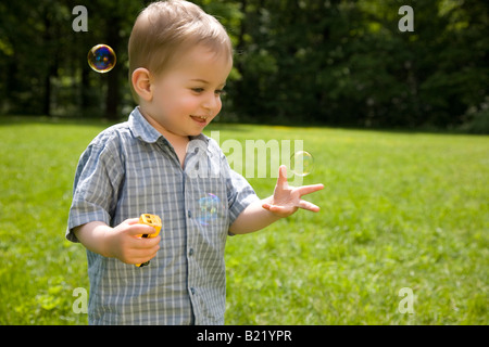 Lachend Kind fängt Seifenblasen Stockfoto