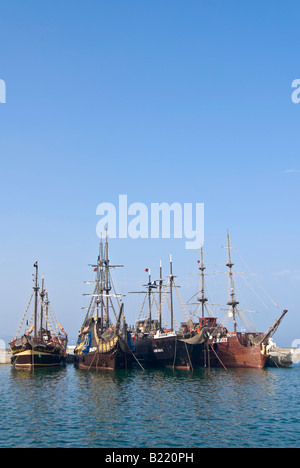 Vertikale Ansicht von vier Galeone Stil Piratenschiffen vertäut nebeneinander in einem Hafen vor blauem Himmel. Stockfoto