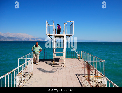 Ein Mann mittleren Alters und eine junge Frau auf einem Pier und Sprungbrett auf See Egirdir, Anatolien, Türkei Stockfoto