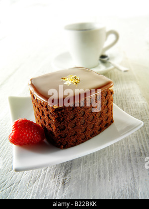 Eine handgemachte Patisserie Spezialität reichen verwöhnenden Schokoladenkuchen mit Kaffee in einem weißen Setting Stockfoto