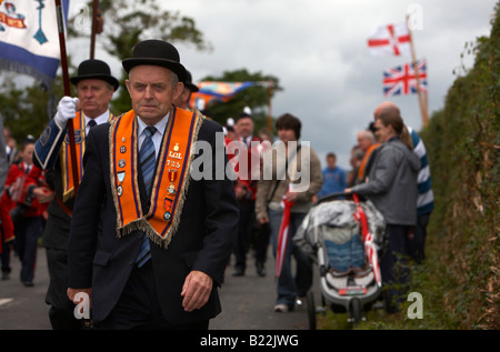 Alter Orangeman tragen Schärpe und Bowler Hut Gasse Land marschieren vorbei Zuschauer während der 12. Juli Orangefest Feierlichkeiten Stockfoto