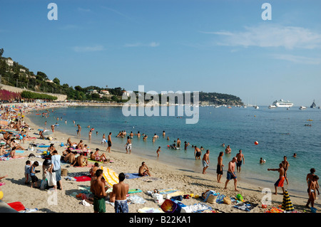 Einheimische und Touristen genießen die späte Nachmittagssonne am goldenen Sandstrand von Villefranche, Frankreich Stockfoto