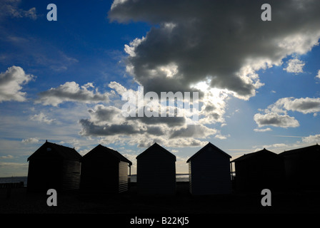 Strandhütten in Silhouette gegen bewölkt blauen Himmel bei Calshot Hampshire England Großbritannien Stockfoto