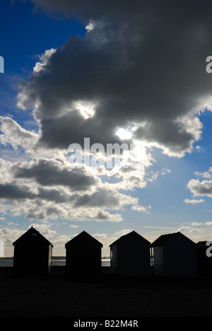 Strandhütten in Silhouette gegen bewölkt blauen Himmel bei Calshot Hampshire England Großbritannien Stockfoto