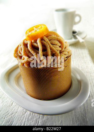 Schokoladenschale gefüllt mit Schwamm und Kastanienmarron Püree einzelnen Kuchen mit einer Tasse Kaffee in einer Tischeinstellung Stockfoto
