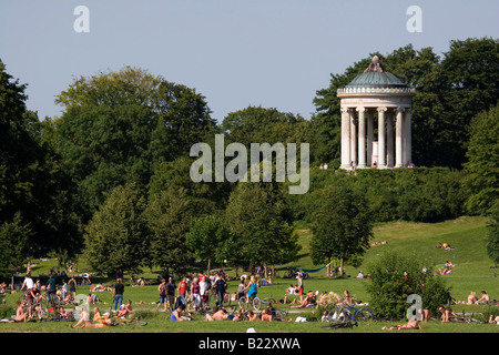 Menschen in den Englischer Garten in München die Sonne genießen. Auf dem Hügel ist der Monopteros zu sehen. Stockfoto