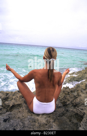 Rückansicht der Frau praktizieren Yoga an Küste Stockfoto