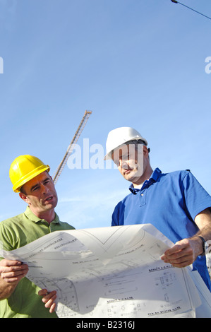 Niedrigen Winkel Ansicht von zwei männlichen Architekten Blaupausen betrachten Stockfoto