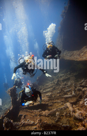 Drei Taucher erkunden das Wrack der Dunraven im Roten Meer. Stockfoto