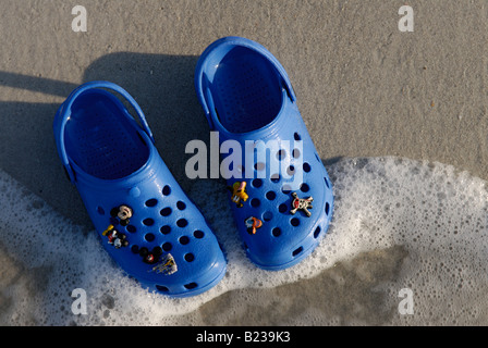 Des Kindes Croc Schuhe am Strand Stockfoto