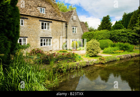 Die Themse fließt vorbei an einem Cotswold Steinhaus im Dorf von Ashton Keynes, Wiltshire, England, UK Stockfoto