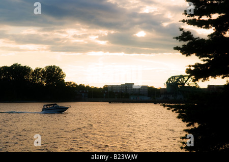 Sportboote Kreuzfahrten entlang eines goldenen Flusses während des Sonnenuntergangs in Kingston, Ontario, Kanada. Stockfoto