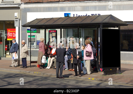 Menschen warten an der Bushaltestelle in High Einkaufsstraße außerhalb Lloyds Bank Stockfoto