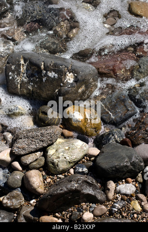 Wellen des Meeres spritzt auf stoney Boulder Felsen am Strand Bucht und Klippen Stockfoto