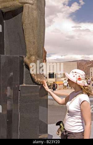 Kaukasische Teengirl reibt Zehen des geflügelten Figuren der Republik am Hoover Dam Nevada, USA Stockfoto