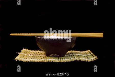 Schüssel mit Reisnudeln in einer schwarzen Schale mit Stäbchen auf schwarzem Hintergrund isoliert Stockfoto