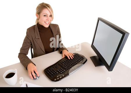 Eine schöne blonde Geschäftsfrau sitzt an ihrem Schreibtisch und arbeiten auf ihrem computer Stockfoto