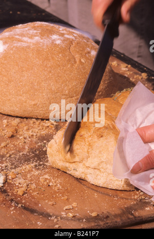 FÜR viele Kulturen Brot ist das ideale SYMBOL der Nahrung HAND schneiden Laib Brot Körner und Getreide Stockfoto