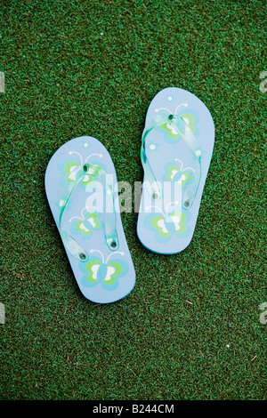 Paar blau Flip flops mit Blumen auf Astro Turf über Kopf gedreht. Stockfoto