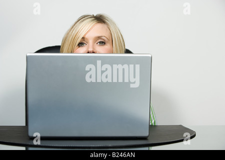 Ein Büroangestellter peeking über einen laptop Stockfoto