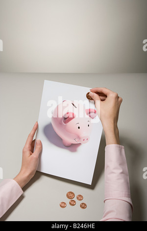 Eine Frau hält ein Foto von einem Sparschwein und Geld Stockfoto