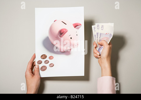 Eine Frau hält ein Foto von einem Sparschwein und Geld Stockfoto