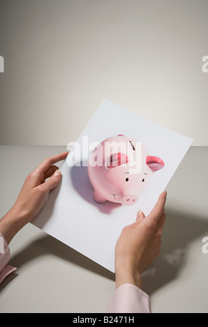 Eine Frau hält ein Foto von einem Sparschwein Stockfoto