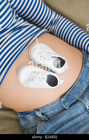 Baby-Schuhe auf dem schwangeren Bauch Stockfoto