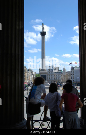 Drei Touristen bewundern die Aussicht des Trafalgar Square von den Stufen der National Gallery in London Stockfoto