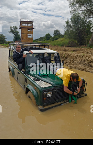 Festsetzung einer Wiederherstellung Riemen für die Verwertung von einen Land Rover Defender stecken in einer Pfütze während off Road in erteilte, Frankreich. Stockfoto