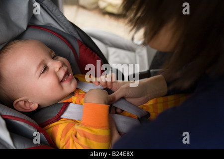 Mutter putting Baby im Autositz Stockfoto