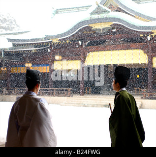 Schneefall hinter zwei Shinto-Priester im Tempel Meiji Jingu - Tokio, Japan Stockfoto