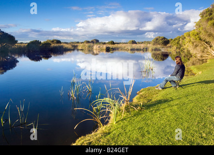 A Mitte der 20er Jahre Frau saß auf einem Schemel neben einem schönen See und Feuchtgebiete. Hirte Lake Regionalpark, Perth, Western Australia, Australia Stockfoto