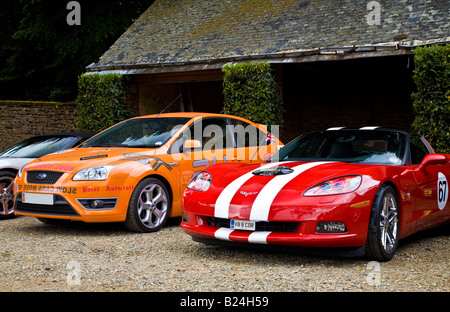 Chevrolet Corvette in roten und weißen Lackierung neben eine orange Ford Focus ST Stockfoto