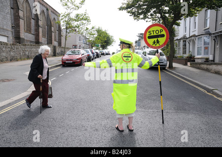Englische Lutscher Dame Führung alte Dame auf der anderen Straßenseite in Falmouth, England Stockfoto