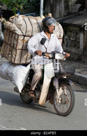 Mann fahren ein Motorrad mit einer schweren Last in Hanoi Vietnam Stockfoto