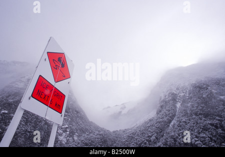 "Beware of Ice" Roadsignwith Hintergrund der Schnee bedeckt Berge entlang der malerischen Milford Road (State Highway 94), Fiordland, NZ Stockfoto