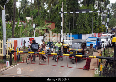 Fahrzeuge warten auf einem Bahnübergang in der Nähe eines Bahnhofs zwischen Kochi Cochin und Kannur Cannanore Kerala Indien Stockfoto