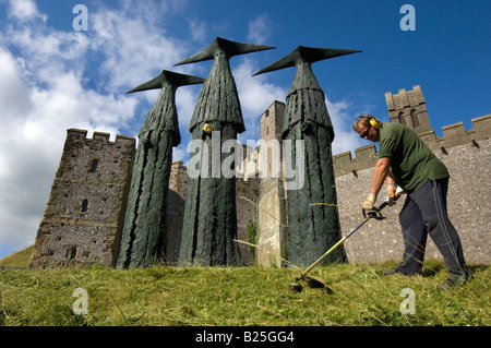 Ein Gärtner schneiden Rasen rund um die Sentinels, Skulpturen von 'Philip Jackson' vor Arundel Castle in Sussex. Stockfoto