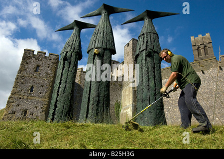 Ein Gärtner schneiden Rasen rund um die Sentinels, Skulpturen von 'Philip Jackson' vor Arundel Castle in Sussex. Stockfoto