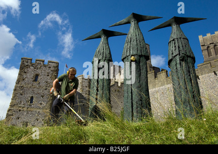 Ein Gärtner schneiden Rasen rund um die Sentinels, Skulpturen von 'Philip Jackson' vor Arundel Castle in Sussex. Stockfoto