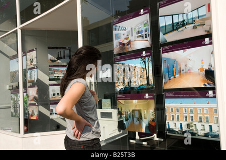 First time junge Käufer Blick auf teure Häuser zum Verkauf in Immobilienmakler Fenster in London England UK Stockfoto