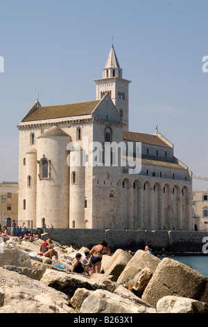 Die Kathedrale - gewidmet St. Nikolaus den Pilger - in Trani, Italien. Menschen zum Sonnenbaden und Schwimmen im Vordergrund. Stockfoto