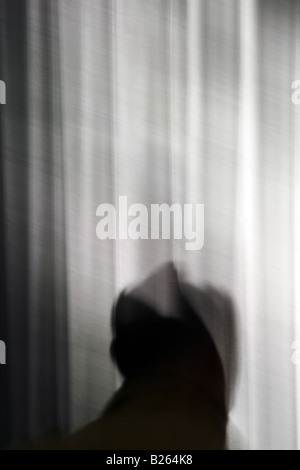 Person und lange dunkle Vorhänge Vorhänge im Zimmer Stockfoto