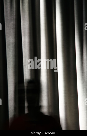 Person und lange dunkle Vorhänge Vorhänge im Zimmer Stockfoto