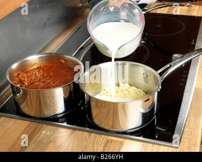 Zubereitung köstliche hausgemachte italienische Hackfleisch Rindfleisch Bolognese Lasagne, mit Milch, um frische Bechamel Sauce auf EINEM heißen Herd zu machen Stockfoto