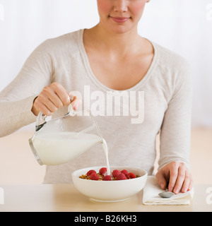 Frau gießt Milch auf Getreide Stockfoto